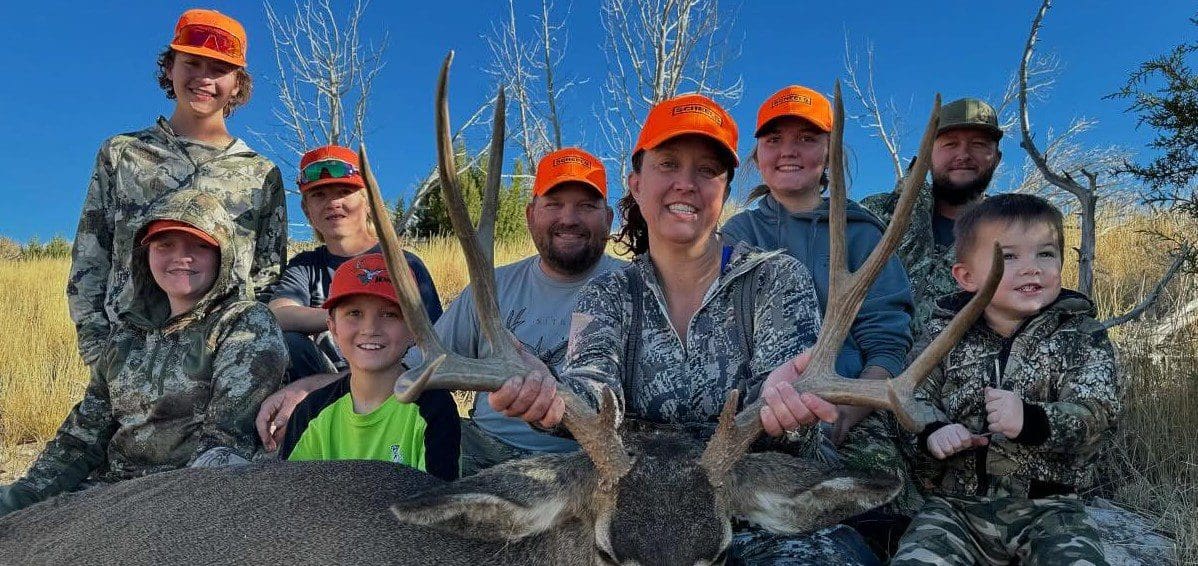 Group of hunters posing with antlered deer